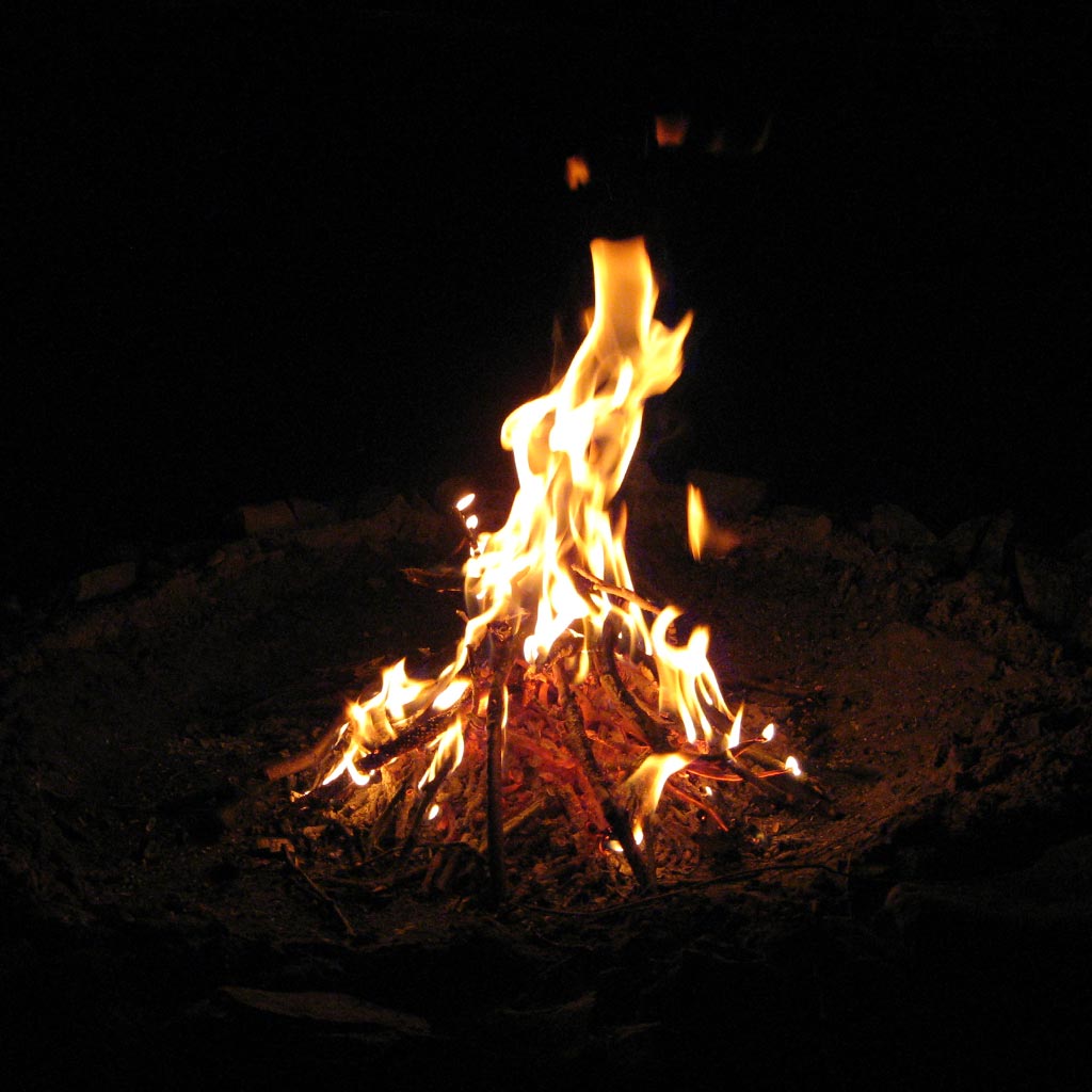 Staring at the flickering flames of a campfire at night.